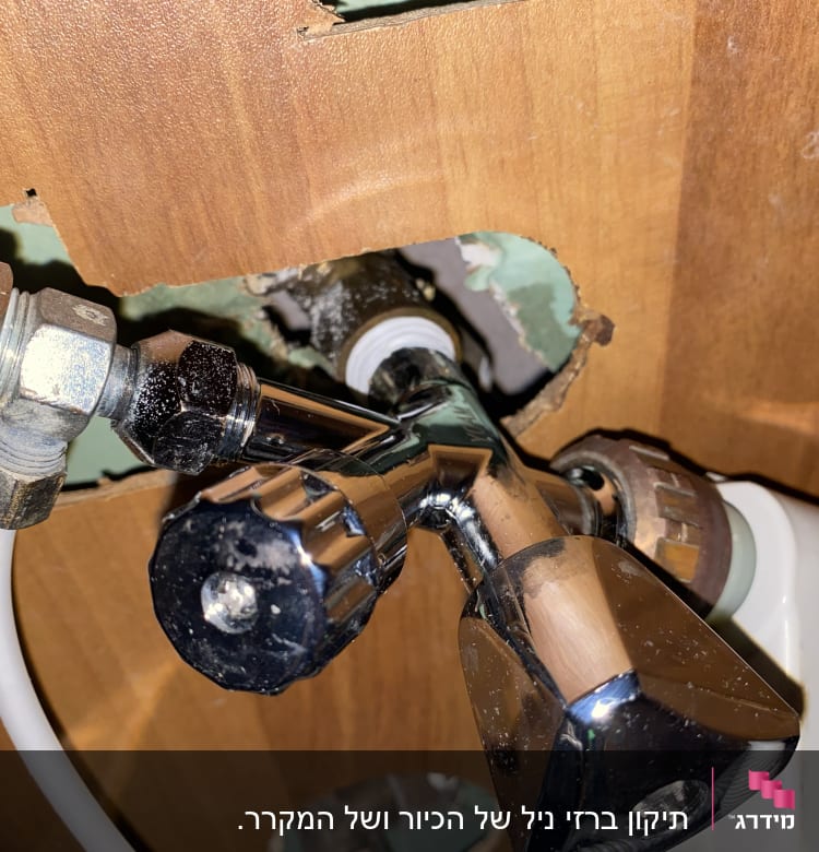 ברז מתכת עם חיבורים וצינור מתחת לכיור